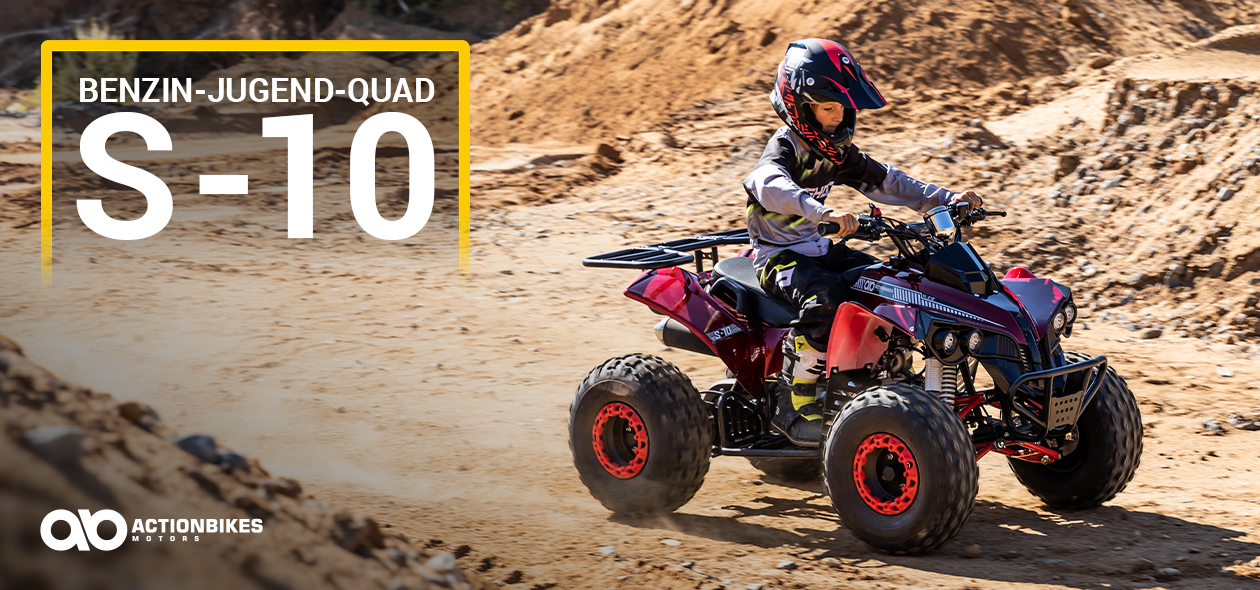 Junge mit Helm braust mit dem Benzin-Jugend-Quad S-10 durch eine sandige Wüste