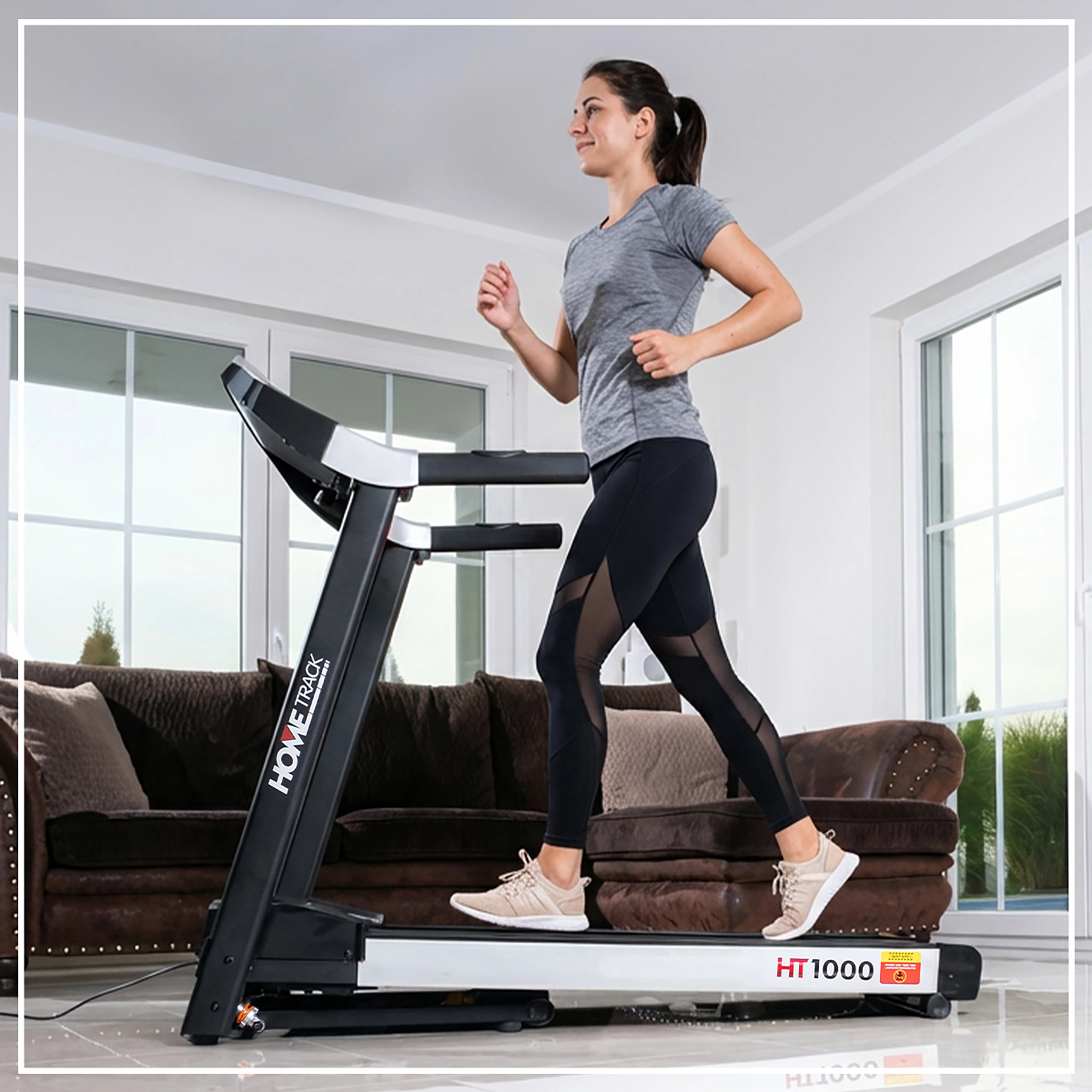 Frau trainiert auf dem Heimtrainer, der sich im Wohnzimmer befindet