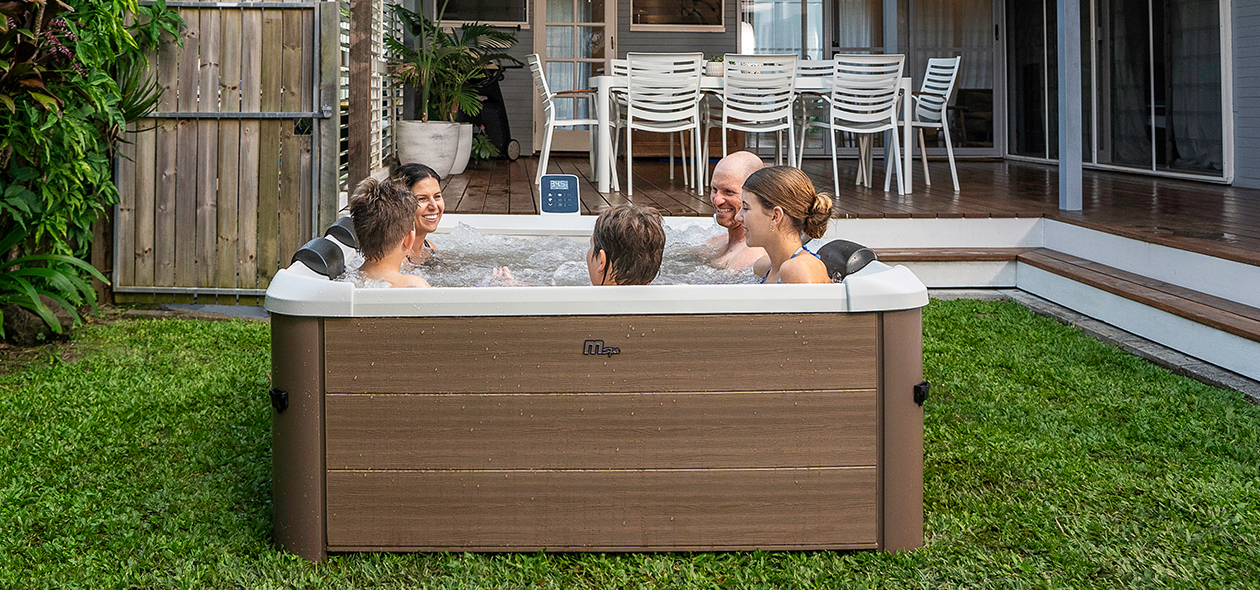 Miweba MSpa Whirlpool Frame Oslo F-OS063W Familie genießt lachend ein sprudelndes Bad im Outdoor-Whirlpool auf der Terrasse