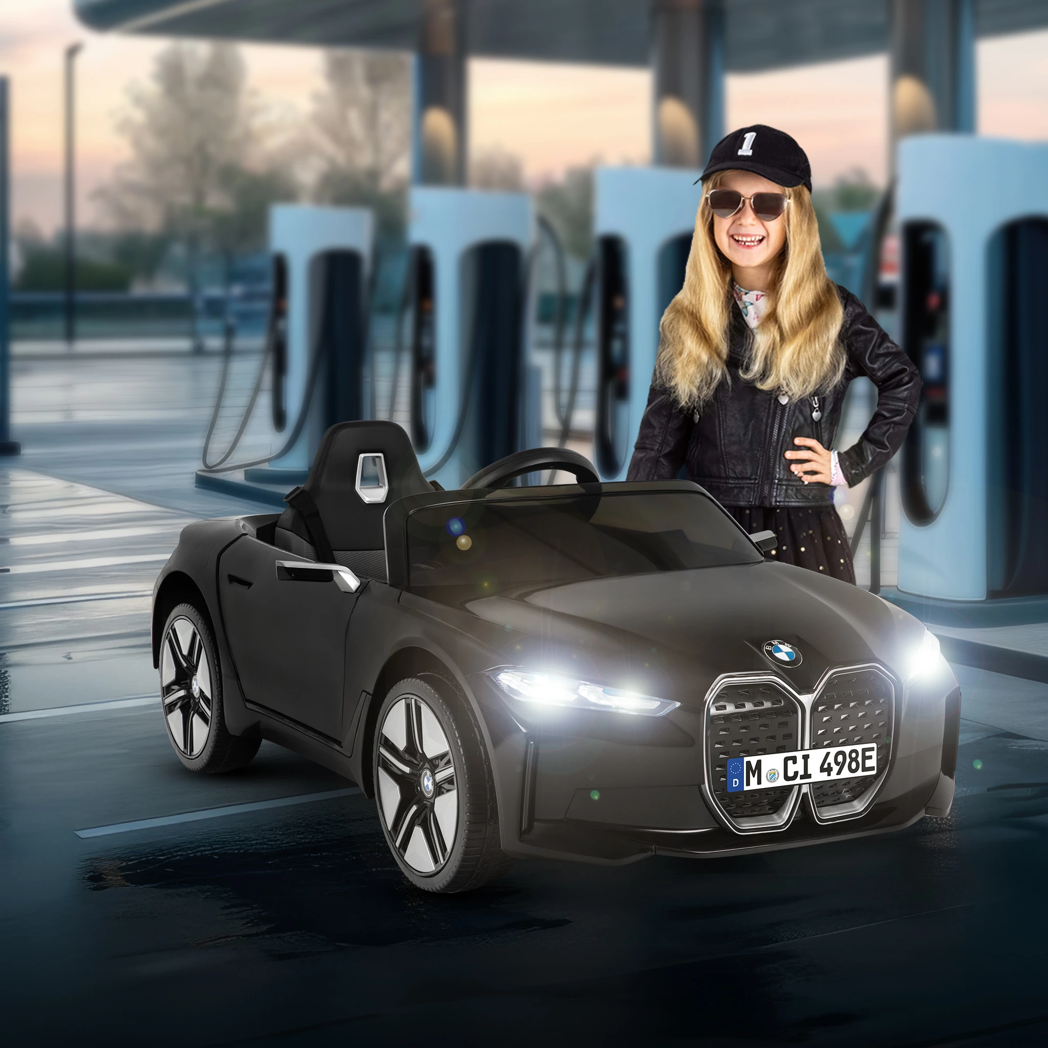 M&auml;dchen steht grinsend neben dem schwarzen Kinder-Elektroauto BMW i4