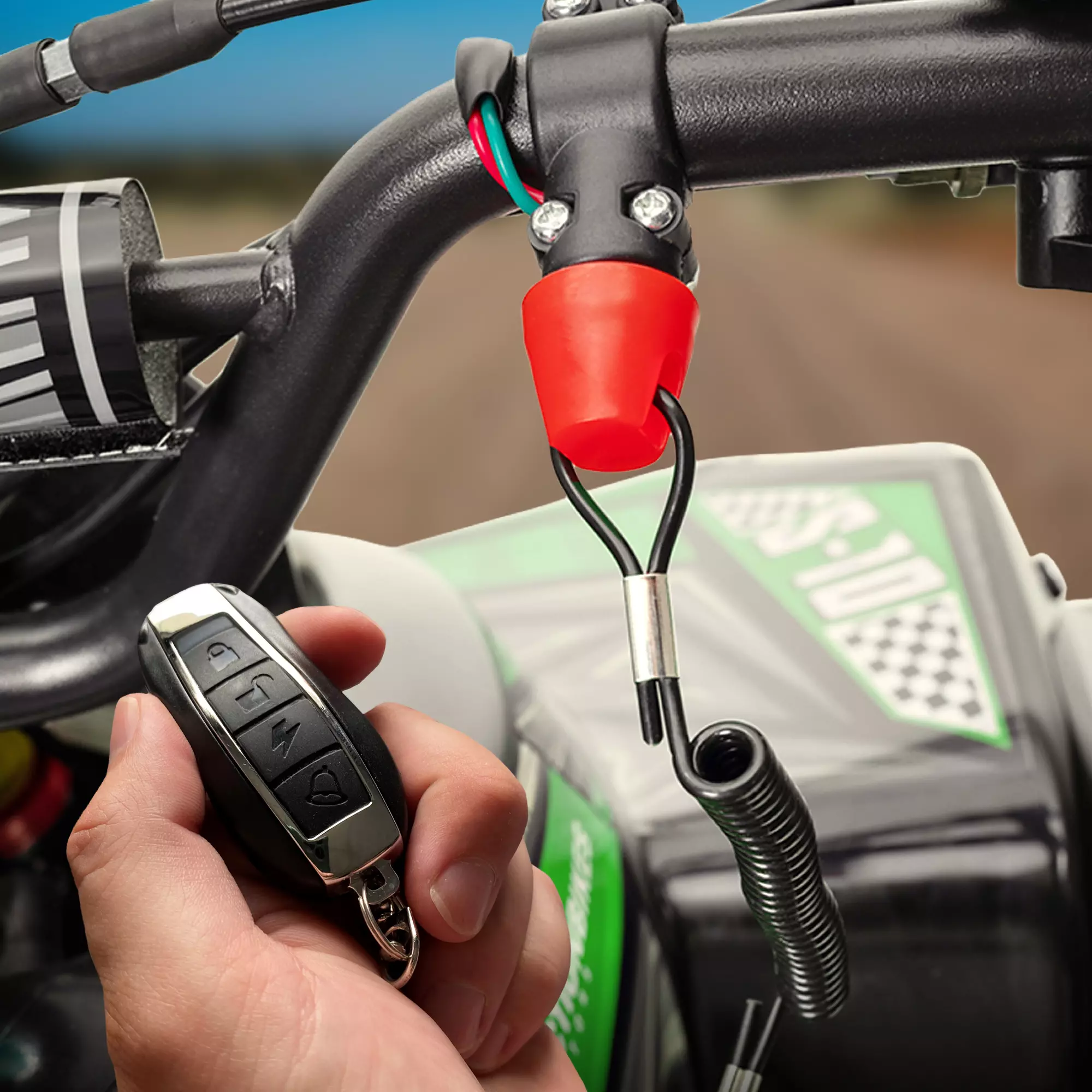 Zusätzlicher Schutz dank Fernbedienung, Not-Aus-Leine und Motorausschalter am Lenker Hand hält die Fernbedienung des Kinderquads neben die am Lenker befestigte Not-Aus-Leine