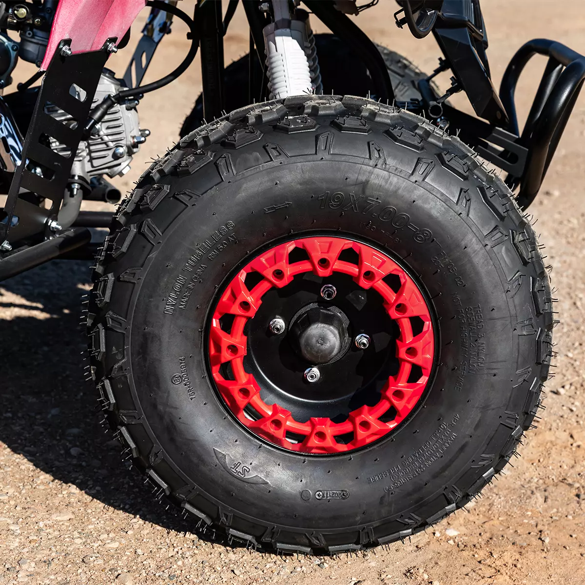 Vergrößerter schwarz-roter Reifen des Kinderquads auf sandigem Boden