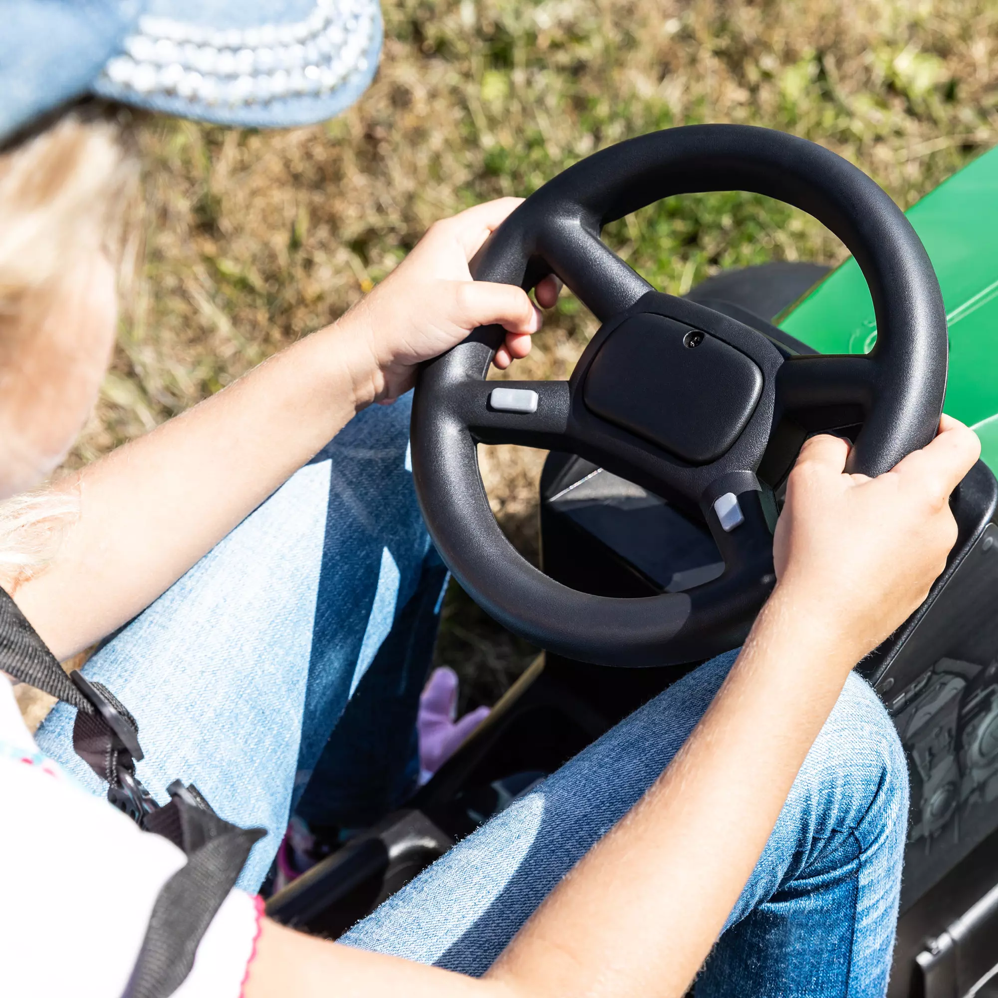 Mädchen hält das Lenkrad des Elektro-Kindertraktors in den Händen