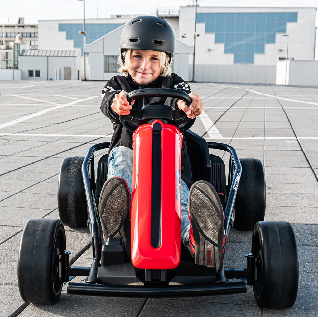Junge sitzt lächelnd im rot-schwarzen Drift-Kart von Actionbikes