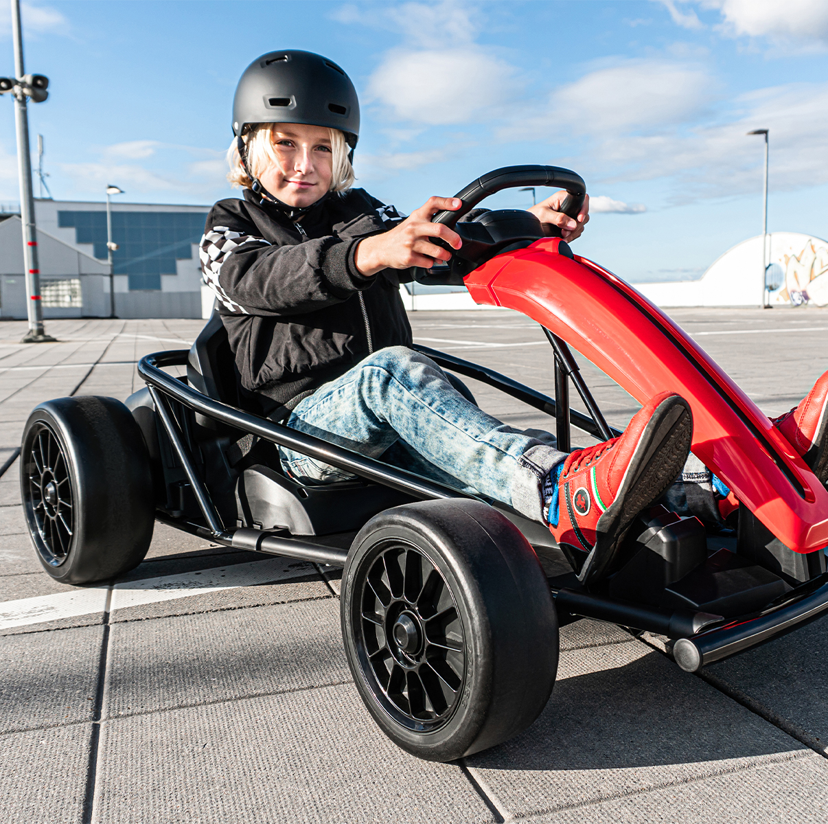 Junge mit Helm steuert das Drift-Kart SX1968 über asphaltierten Boden