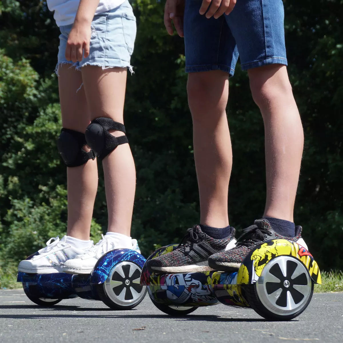 Beine eines Mädchens und eines Jungen auf je einem Self-Balance-Scooter
