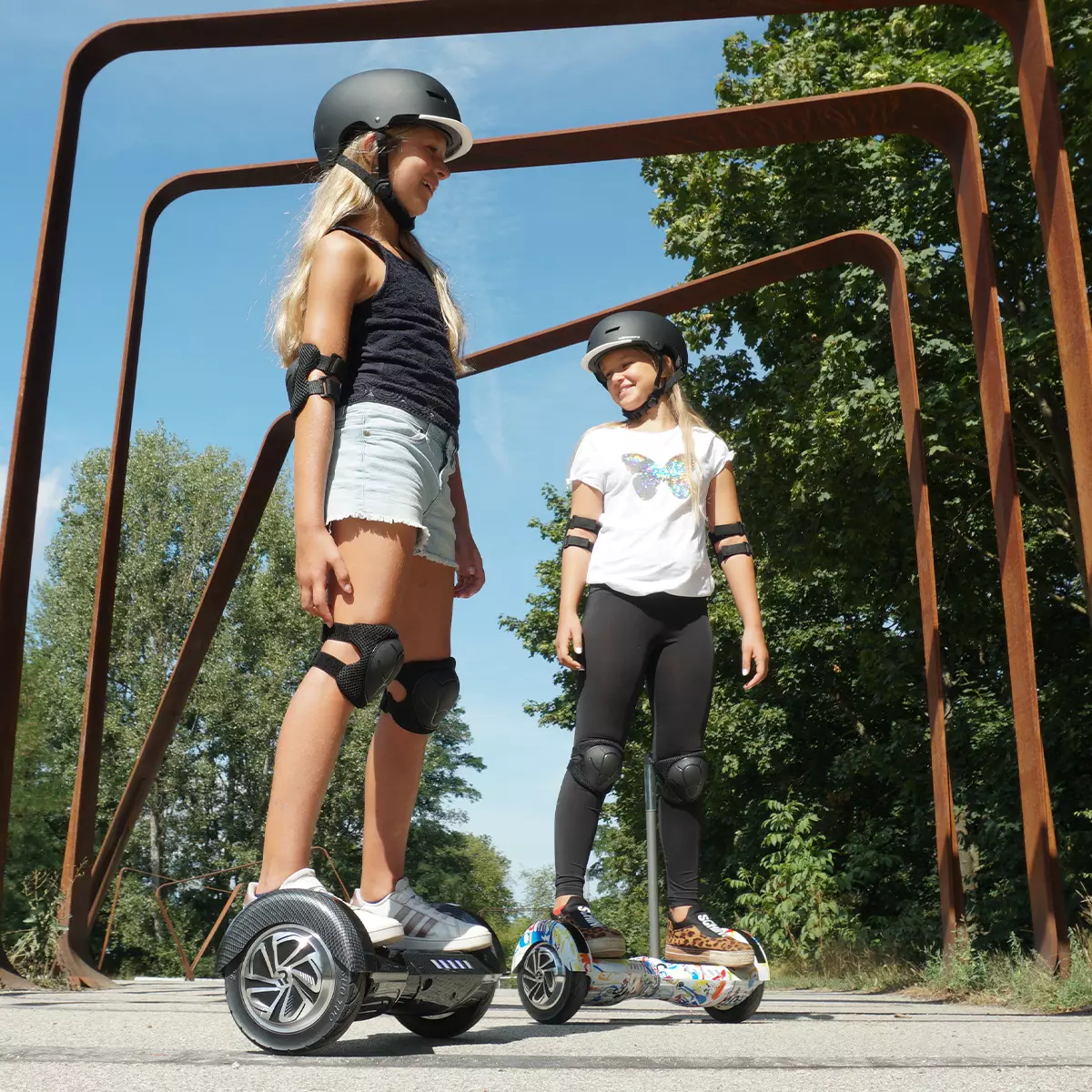 Zwei Mädchen steuern lächelnd die Hoverboards von Robway durch den Park