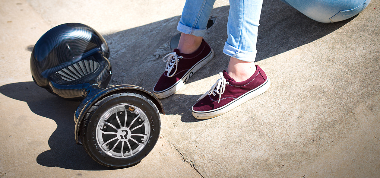 Mädchen sitzt auf Boden, vor seinen Füßen liegt das Robway W3 Hoverboard