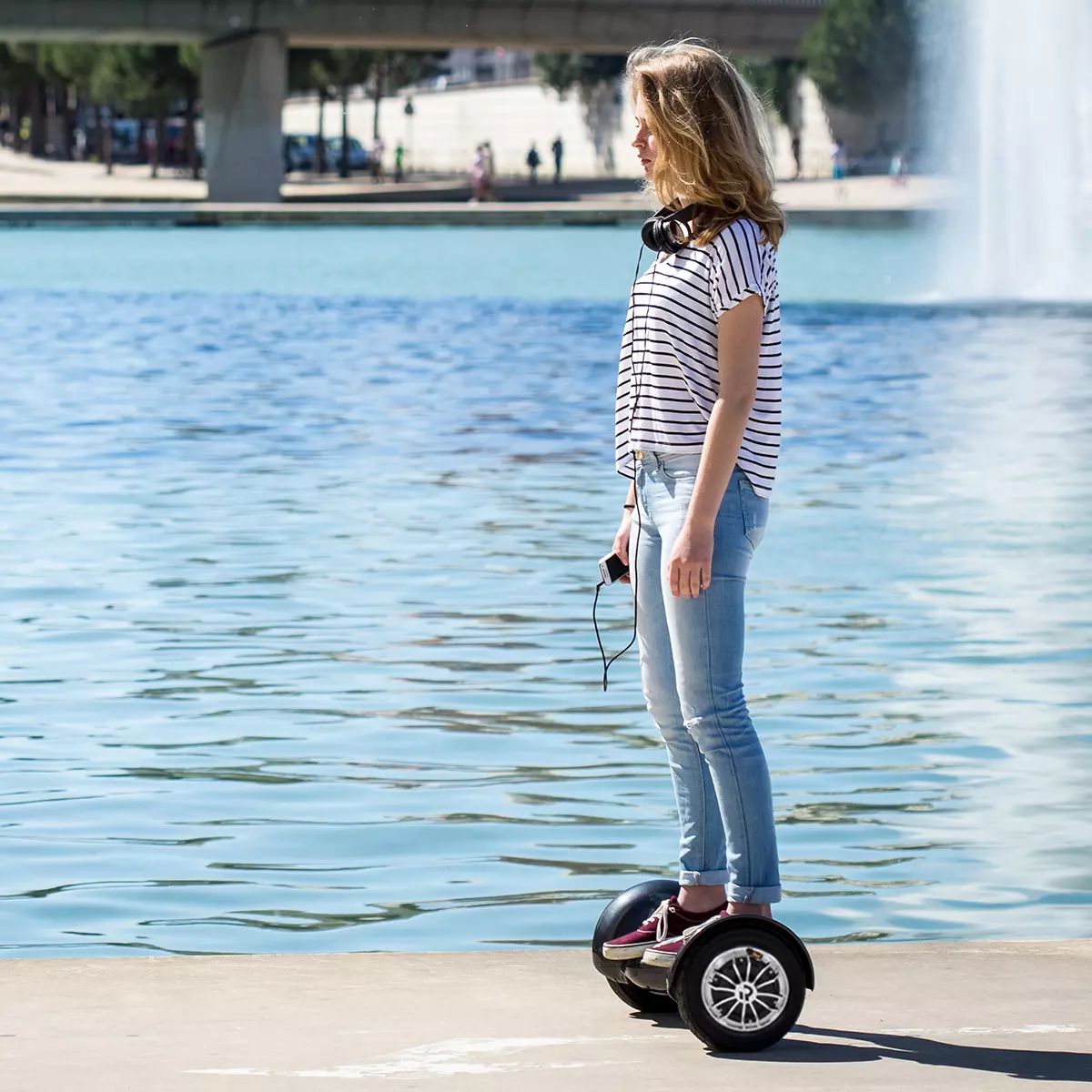 Mädchen fährt mit dem Self-Balance-Scooter am Strand neben dem Wasser entlang